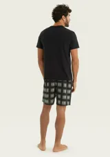 Pijama para hombre compuesto por una remera lisa de manga corta y cuello en V de color negro, combinada con un short a cuadros en tonos oscuros con cintura elástica.