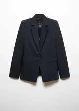 Blazer entallado de color negro con solapas de muesca, hombros estructurados y cierre frontal de un botón. Cuenta con bolsillos de ribete delanteros, detalle de pinzas y abertura posterior.
