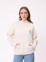 Canguro color crema con capucha y estampado grande en la espalda de un sol con un ojo, montañas, mariposas y texto.