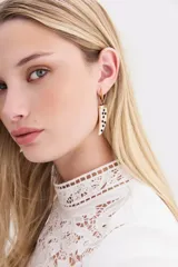 Aros colgantes compuestos por una argolla dorada pequeña y un dije de resina en forma de cuerno con incrustaciones de strass negro.