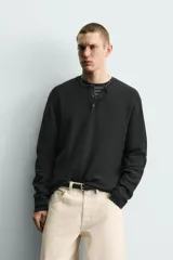 Jersey relaxed fit de punto acanalado color marrón oscuro, con cuello redondo tipo panadera y cierre frontal de tres botones. Tiene manga larga y efecto lavado.