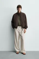 Cazadora bomber reversible de corte relaxed fit, color marrón oscuro, con cuello alto, cierre frontal de cremallera, bolsillos laterales de vivo y acabados elásticos en puños y dobladillo.