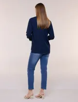 Camisa blanca de corte clásico y caída fluida, con cuello camisero tradicional, abotonadura frontal oculta y mangas largas con puños anchos.
