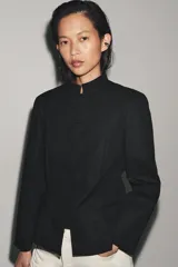Blazer negro de mezcla de algodón, con cuello subido y manga larga. Cuenta con falsos bolsillos de vivo en el delantero y cierre frontal con alamares a tono.