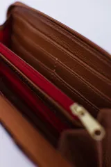 Billetera rectangular con cierre perimetral, confeccionada en cuero con textura de reptil. Cuenta con múltiples compartimentos internos para tarjetas, documentos y billetes, además de un bolsillo interior con cierre para monedas.