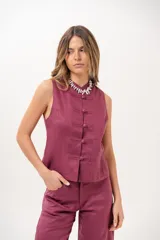Chaleco sin mangas de color magenta, con cuello redondo y cierre frontal de botones tipo nudo chino.