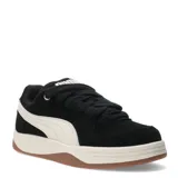 Championes Puma modelo Park Luna SD, de estilo urbano con inspiración skate. Presentan una capellada de gamuza negra con la icónica franja lateral de Puma en color blanco, cordones gruesos, entresuela de goma en tono crema y suela de caucho color caramelo.