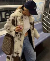 Tapado midi de piel sintética con estampado de manchas tipo vaca en tonos blanco y marrón. Presenta cuello amplio, cierre frontal con botones y corte recto de ajuste relajado.