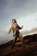 Blusa color ocre con estampado de flores, escote en V, mangas largas abullonadas con lazo en los puños y corte holgado.