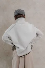 Sweater de punto color gris claro, con cuello alto, mangas largas y corte holgado.