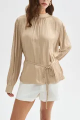 Blusa de poliéster color negro con cuello alto, mangas largas, diseño holgado, detalles de frunces y lazo ajustable en la cintura.