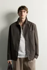 Sobrecamisa regular fit color marrón oscuro de algodón con estructura canvas, cuello solapa, manga larga, bolsillos frontales de parche y cierre de botonadura. Forro interior a cuadros en tonos marrón y beige.