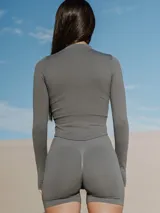 Chaqueta deportiva de manga larga color gris antracita, con cuello alto, cierre frontal completo y detalle de abertura para el pulgar en los puños.