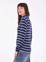 Polera blanca con rayas horizontales negras, cuello alto y mangas largas.