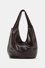 Bolso de hombro tipo saca en formato maxi, confeccionado en material sintético con acabado liso. Presenta un diseño holgado con asa de hombro integrada, cierre imantado en el compartimento principal, bolsillo interior con cremallera y bolsillo lateral exterior con cremallera y tirador.