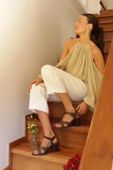 Sandalias de cuero color marrón, con taco cuadrado y plataforma baja. Presentan tiras anchas cruzadas en el empeine con apliques metálicos circulares y una tira ajustable con hebilla alrededor del tobillo.