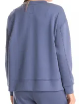 Buzo deportivo de cuello redondo, con hombros caídos y mangas largas con puños. Presenta costuras decorativas tipo pespunte en la parte frontal y en las mangas, con un diseño de ruedo recto y tajos laterales.