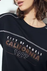 Remera negra de manga corta con estampado tipográfico "City of Angels California 1997" en tonos marrones y costuras visibles en blanco.