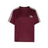 Remera de manga corta Adidas modelo Firebird, color bordó con las icónicas tres tiras blancas en los hombros y mangas, y el logo del trébol bordado en el pecho.