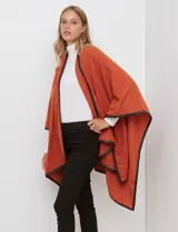 Ruana color naranja, de tejido suave, con vivos en ecocuero negro.