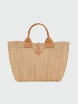 Bolso tipo shopper de gran tamaño, confeccionado en rafia natural con detalles de cuero en tono beige claro. Presenta asas superiores de cuero, cierre de broche tipo toggle con tira de cuero y estructura rígida.