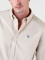 Camisa lisa de hombre color celeste, confeccionada en algodón con acabado vintage, corte regular fit, cuello button-down, cierre frontal de botones y logo bordado en el pecho.