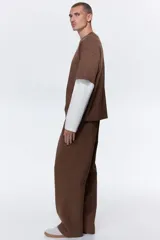 Pantalón deportivo de felpa marrón con elástico en la cintura, cordón de ajuste y bolsillos laterales, corte holgado.