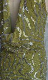 Vestido corto ajustado color verde lima, con escote pronunciado en V tipo drapeado y tirantes finos. El vestido está cubierto de lentejuelas plateadas.