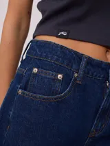 Bermuda de jean azul oscuro, corte recto y largo hasta la rodilla. Confeccionada en denim 100% algodón, con bolsillos delanteros y traseros.