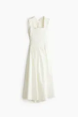 Vestido midi blanco de popelina de algodón, con cuerpo fruncido tipo nido de abeja, escote cuadrado y tirantes anchos con volantes que se cruzan en la espalda. Falda con ligero vuelo.