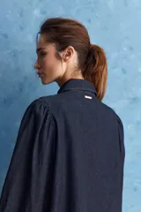 Camisa de jean azul oscuro con calce relajado, cuello clásico, bolsillo aplicado en el delantero y mangas largas abullonadas con puños abotonados.