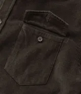 Camisa de hombre color verde oscuro, confeccionada en terciopelo, con cuello clásico, manga larga y dos bolsillos frontales con solapa y botón. Cierre frontal con botones.