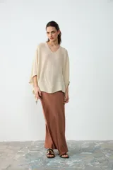 Poncho corto de tejido liviano en color crudo, con escote en V y diseño amplio y fluido.