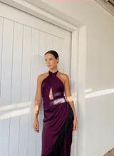 Vestido largo de seda lavada color violeta, con escote halter cruzado y abertura frontal. La falda presenta un diseño en capas con detalle de flecos laterales.