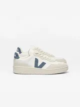 Championes Veja V-90 O.T. Leather de hombre, en color blanco con detalles en azul oscuro y superposiciones de gamuza gris claro en la puntera y el talón. Presenta la clásica letra 'V' de la marca en el lateral y suela de goma.