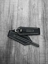 Faja ancha de cuero sintético negro con elástico en la parte trasera y tachas plateadas.