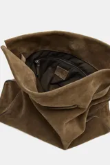 Maxi bolso de hombro confeccionado en serraje, con diseño de silueta holgada y detalle de tira entrelazada en la parte frontal. Cuenta con asa de hombro, cierre mediante botón imantado y bolsillo interior con cremallera.