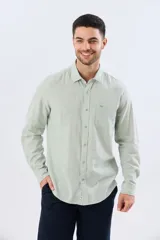 Camisa de lino de manga larga en color beige, con cuello camisero, cierre frontal de botones y un bolsillo ojal en el pecho.