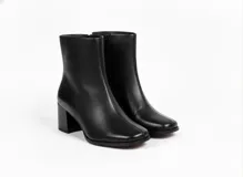 Botas de caña corta confeccionadas en cuero negro con textura granulada, diseño de punta cuadrada y taco bloque de altura media.