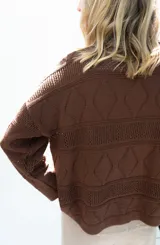 Cardigan de punto color marrón, abierto con botones imitación hueso, manga larga con parche bordado y diseño texturado.