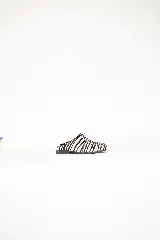 Zueco de cuero con estampado animal print de cebra, diseño de punta cuadrada y detalle metálico lateral. Cuenta con suela de caucho.