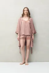 Bata de pijama negra de tejido satinado con leve elasticidad, silueta fluida y estilo envolvente. Presenta diseño cruzado con lazo regulable en la cintura y mangas amplias.