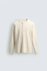 Camiseta de manga larga en tejido acanalado color beige, con cuello panadero y cierre de botones en el frente.