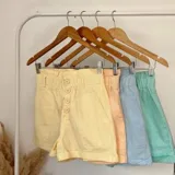 Short color amarillo pastel con cintura elastizada y detalle de botones frontales.