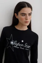 Remera de manga larga con efecto lavado, cuello redondo y estampa frontal con diseño de estrella y texto.