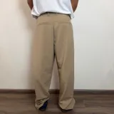 Pantalón sastrero color beige, de corte baggy, con pliegues en la cintura y bolsillos laterales.