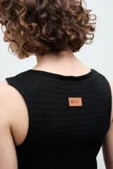 Chaleco negro de punto con escote en V y cierre frontal con dos ganchos metálicos.