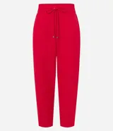 Pantalón de crepé rojo, modelo estilo pijama, de corte fluido, con cintura elástica y lazo de ajuste con terminales metálicas. Cuenta con bolsillos laterales y cierre frontal con cremallera y botón.