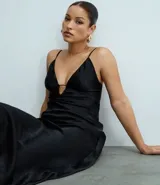 Vestido largo negro de satén con escote pronunciado en V y detalle de recorte central en el busto. Posee breteles finos ajustables y silueta alargada con leve cola en el ruedo.