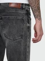 Jean de corte recto y tiro medio, confeccionado en denim de algodón con efecto lavado en tono gris oscuro. Presenta cierre de botón y cremallera, con diseño clásico de cinco bolsillos.